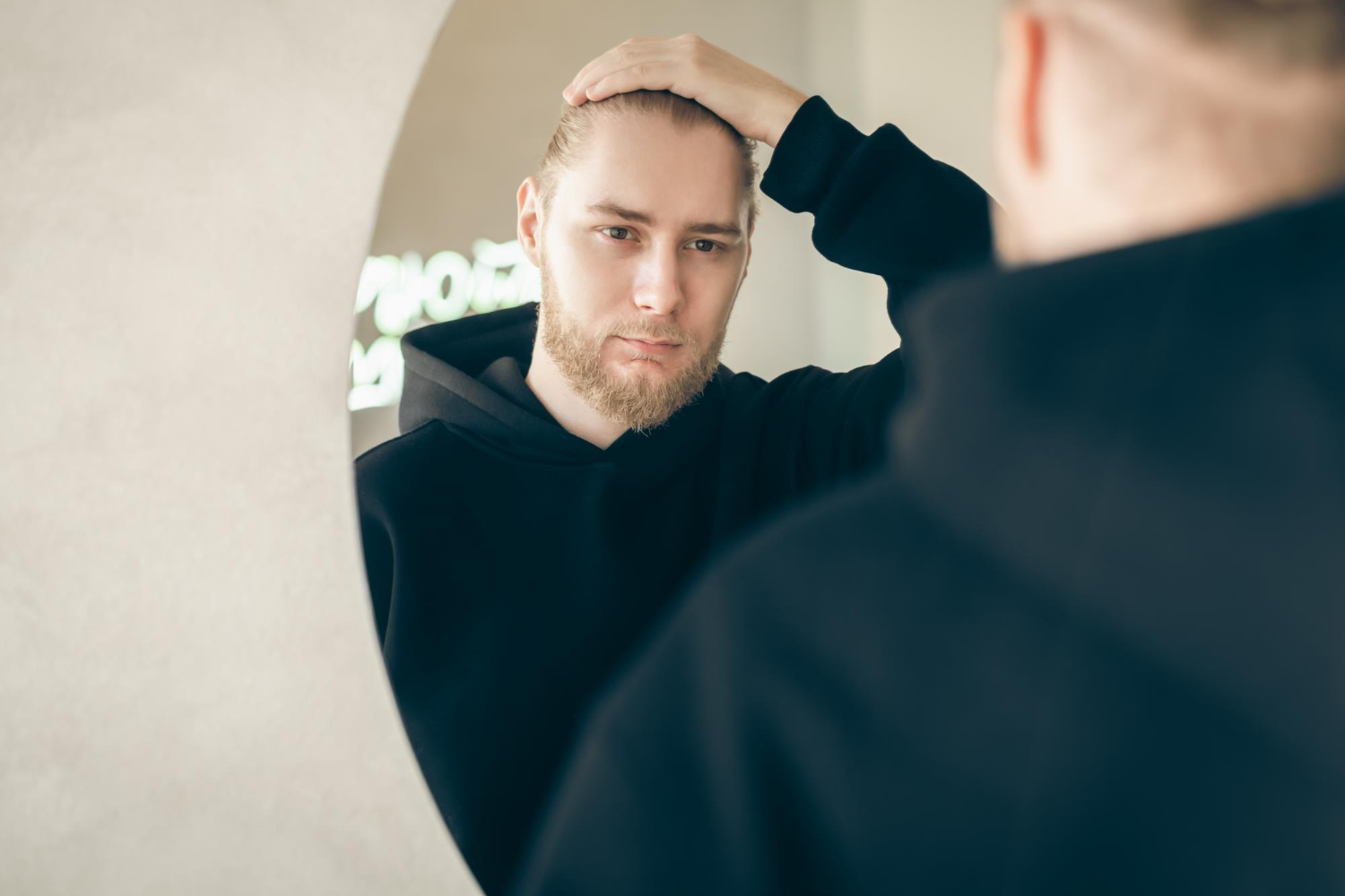 hair loss treatment men — man checking thinning hair in mirror